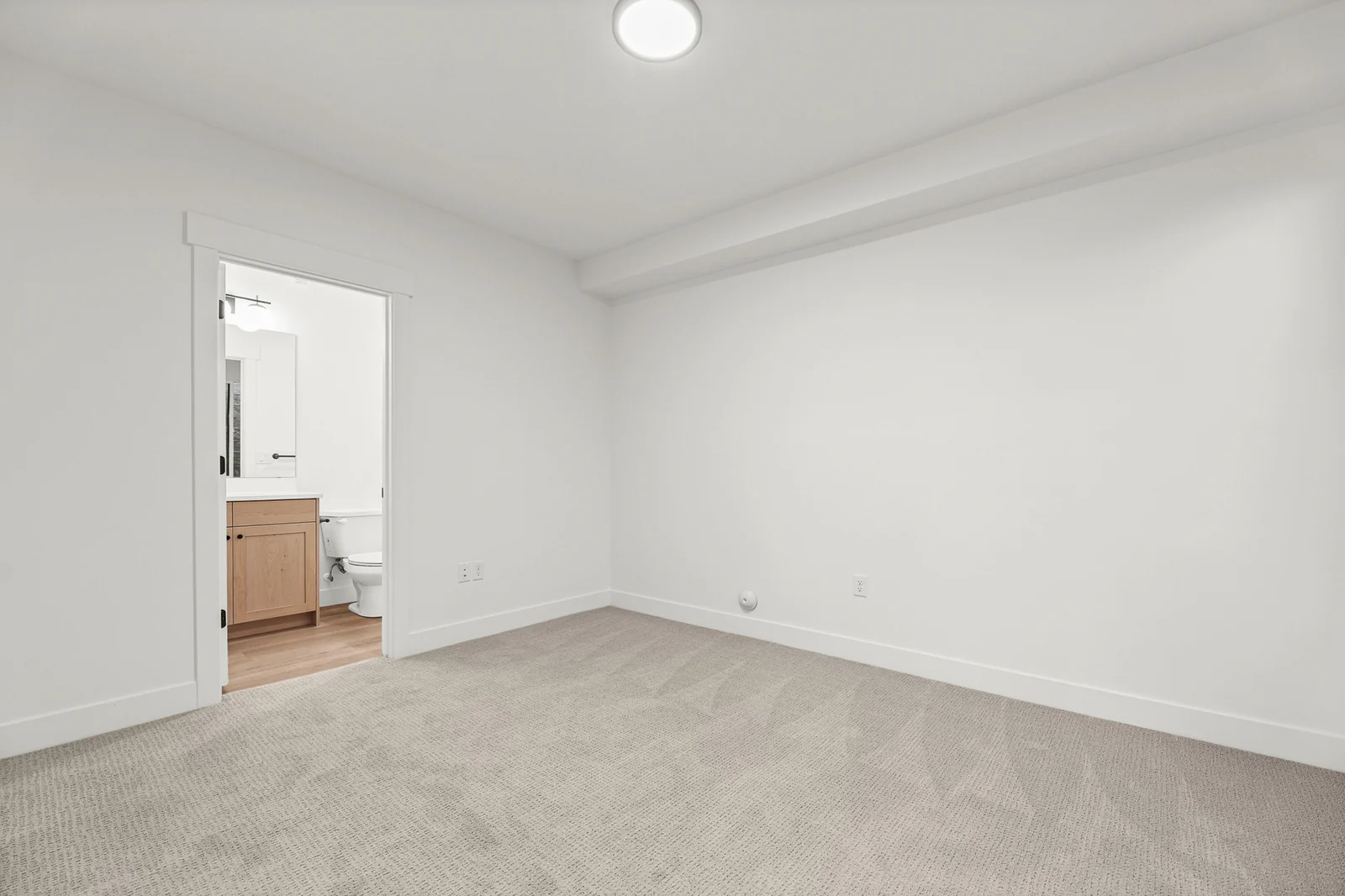 Unfurnished carpeted lower-level bedroom with white walls, recessed lights, a window, and open doorway in Hawthorne Modern, Ogden.