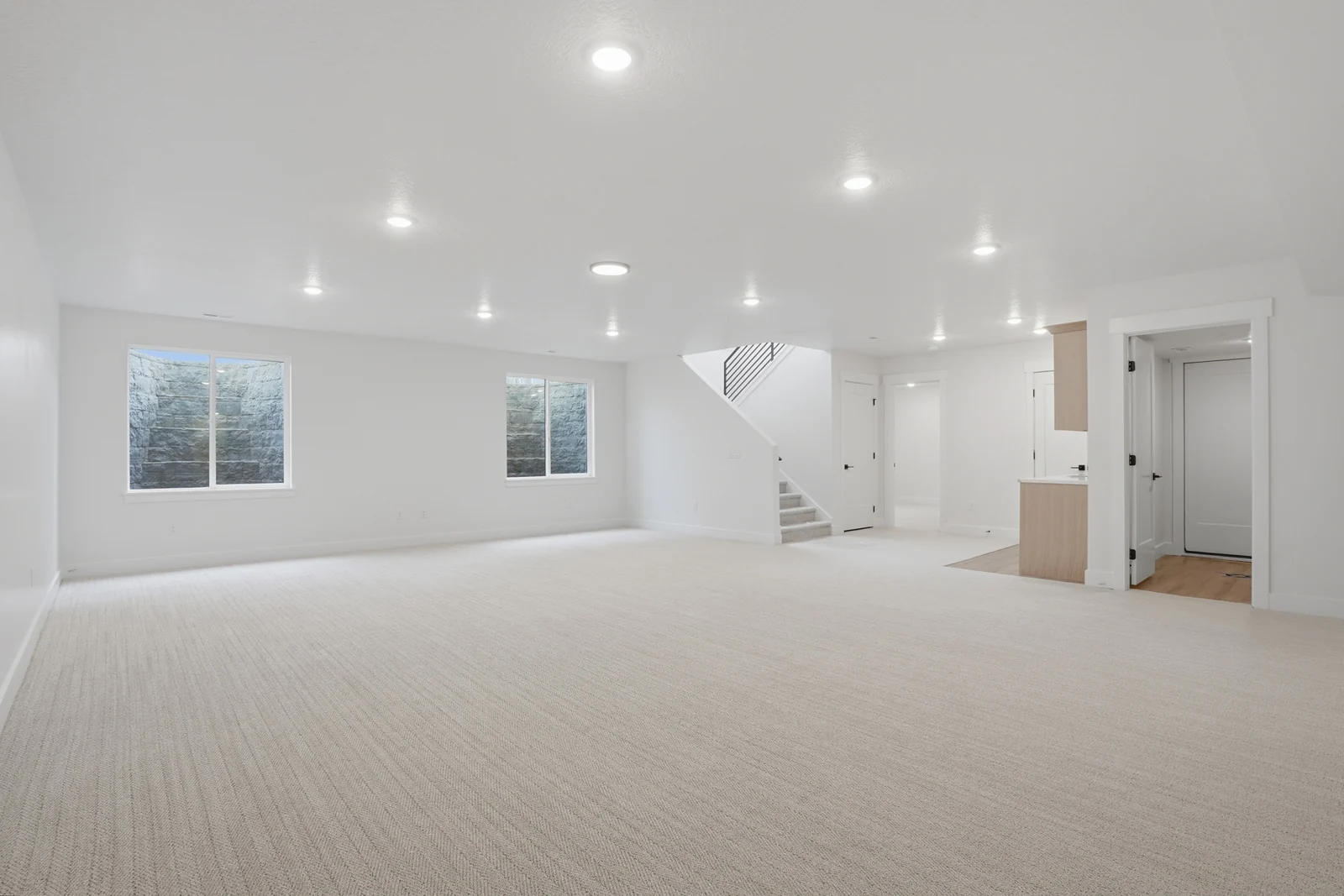 Spacious lower-level rec room with recessed lights, neutral carpet, windows, and an open plan in Olympic BH08, American Fork.