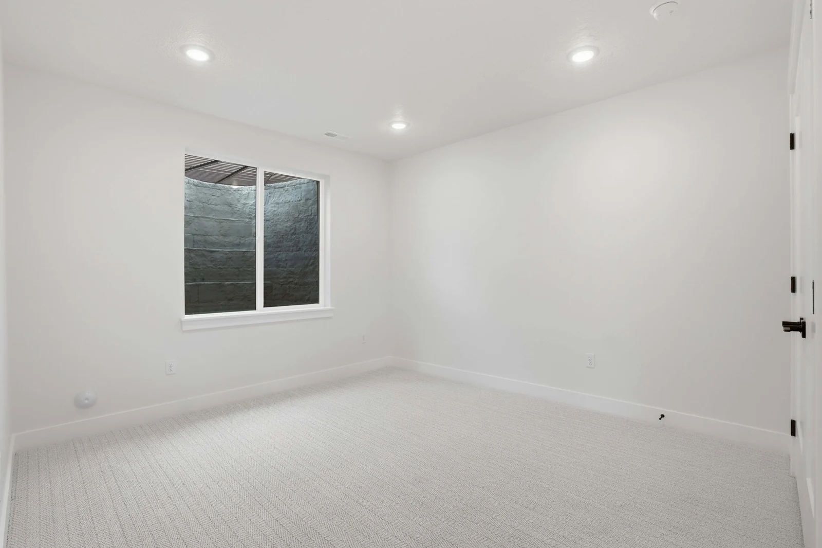 Unfurnished bedroom with pale carpet, recessed lighting, white double closet doors, and a wide window in the Denali model, American Fork.