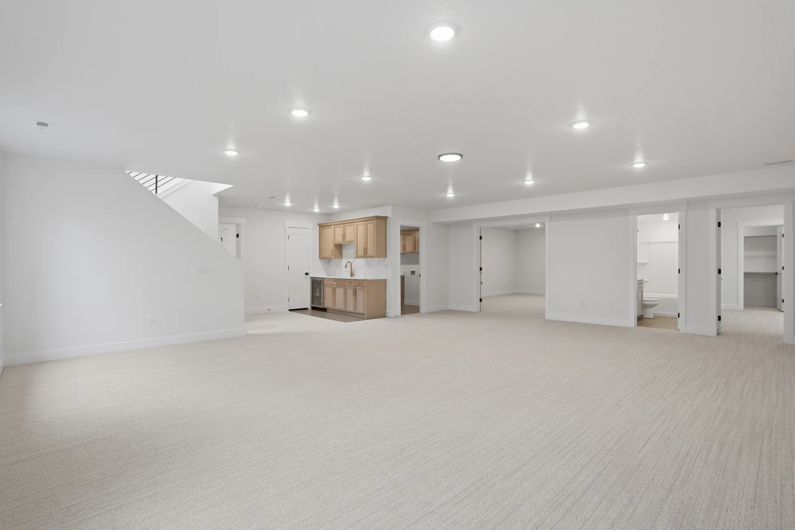 Lower-level rec room facing a compact beverage bar, stair opening, and interior doors in Olympic BH08, American Fork.