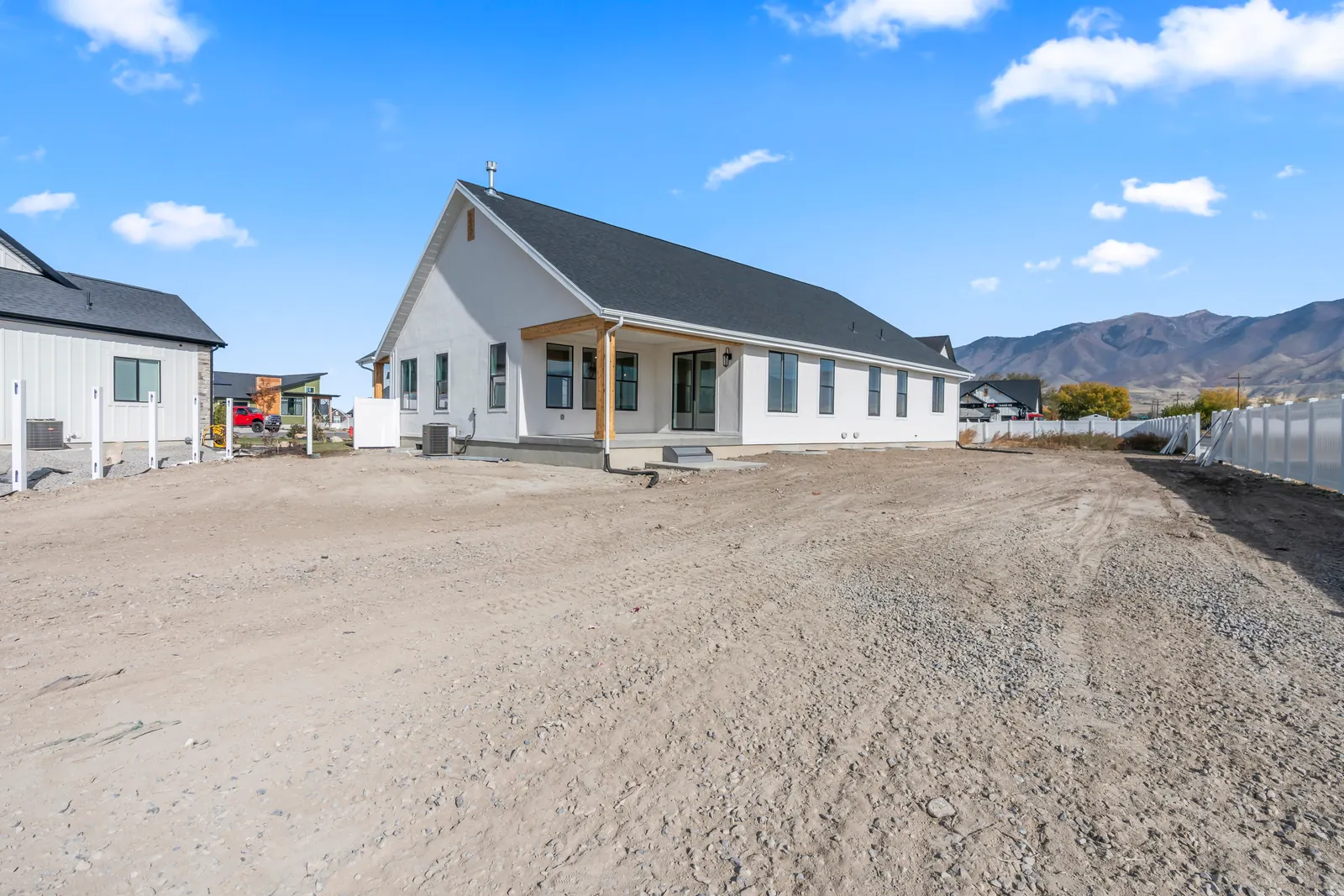 Angled rear corner view showing the covered patio, white siding, windows, and distant mountains at Chestnut MW311, Stansbury Park.