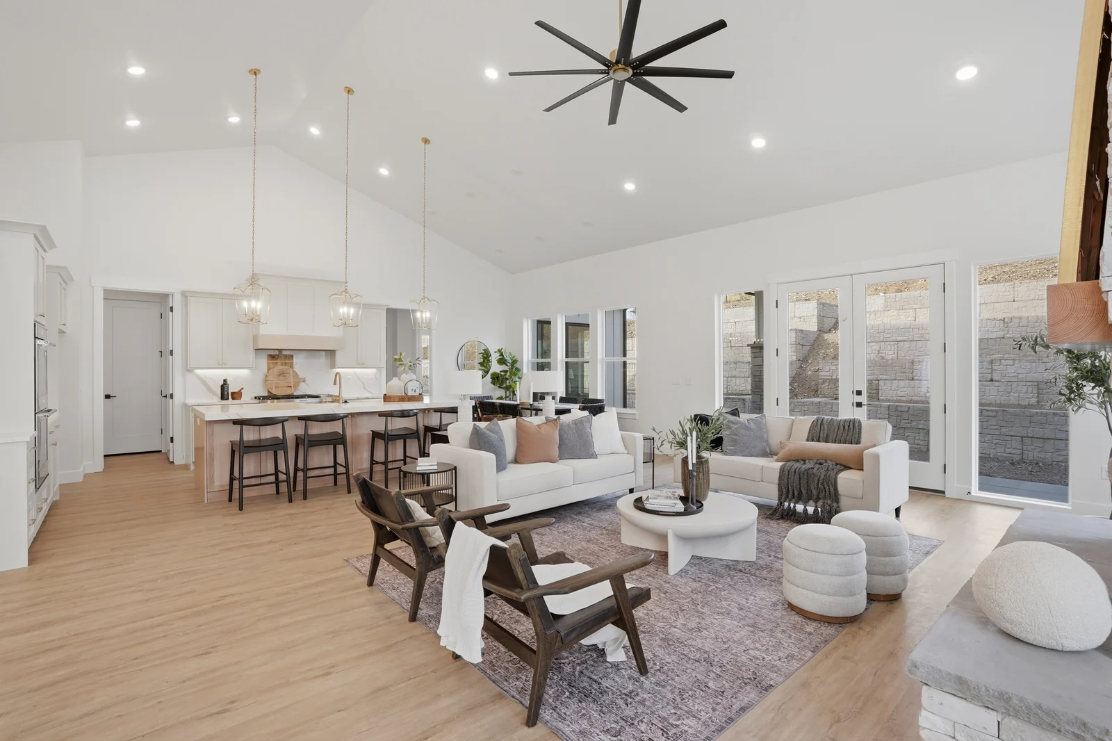 Open great room with kitchen island, dining table, white seating, fireplace, and pendant lights in Olympic BH08, American Fork.