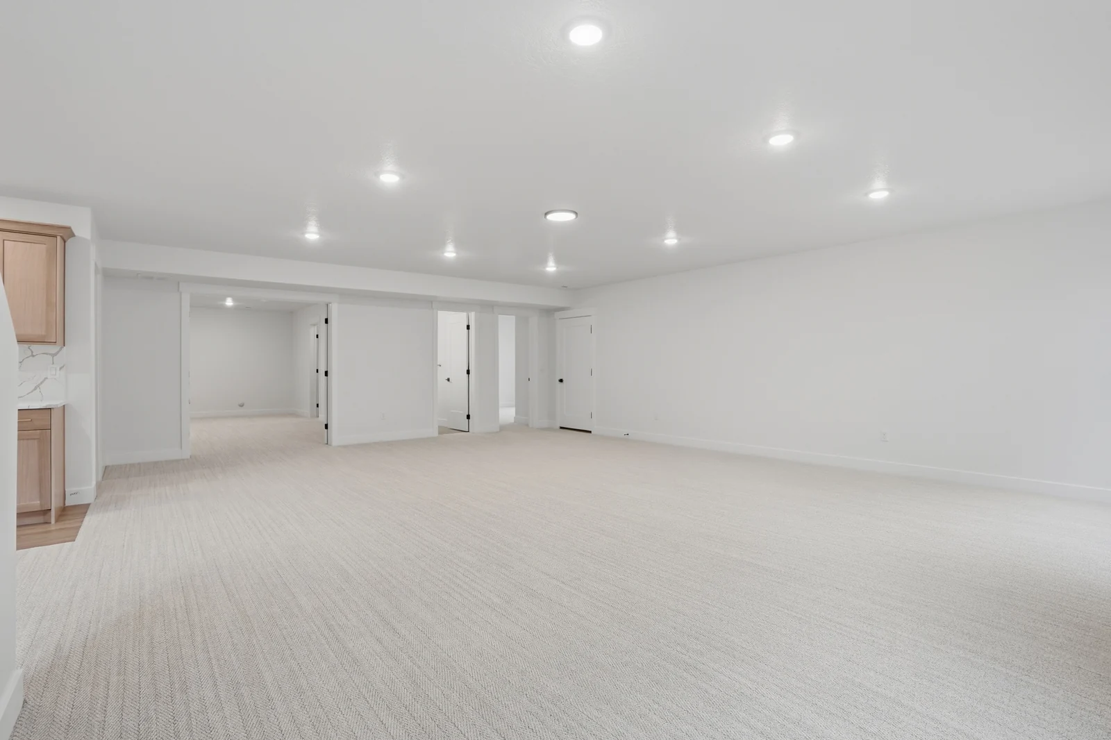 Alternate lower-level rec room view with recessed lighting, neutral carpet, doors, and a beverage bar in Olympic BH08, American Fork.