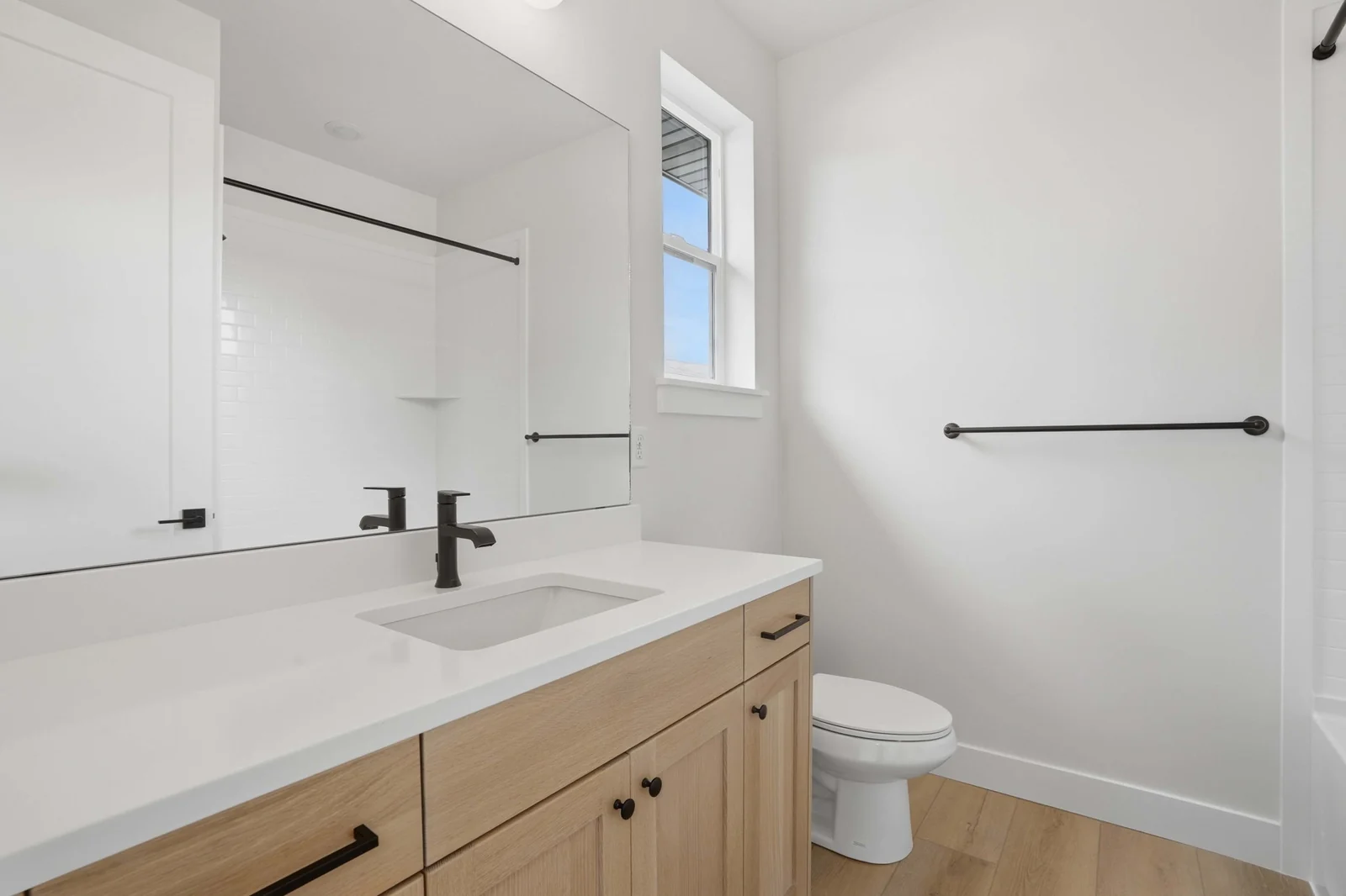 Bathroom with a single wood vanity, white countertop, rectangular mirror, toilet, and towel bar in the Denali model, American Fork.