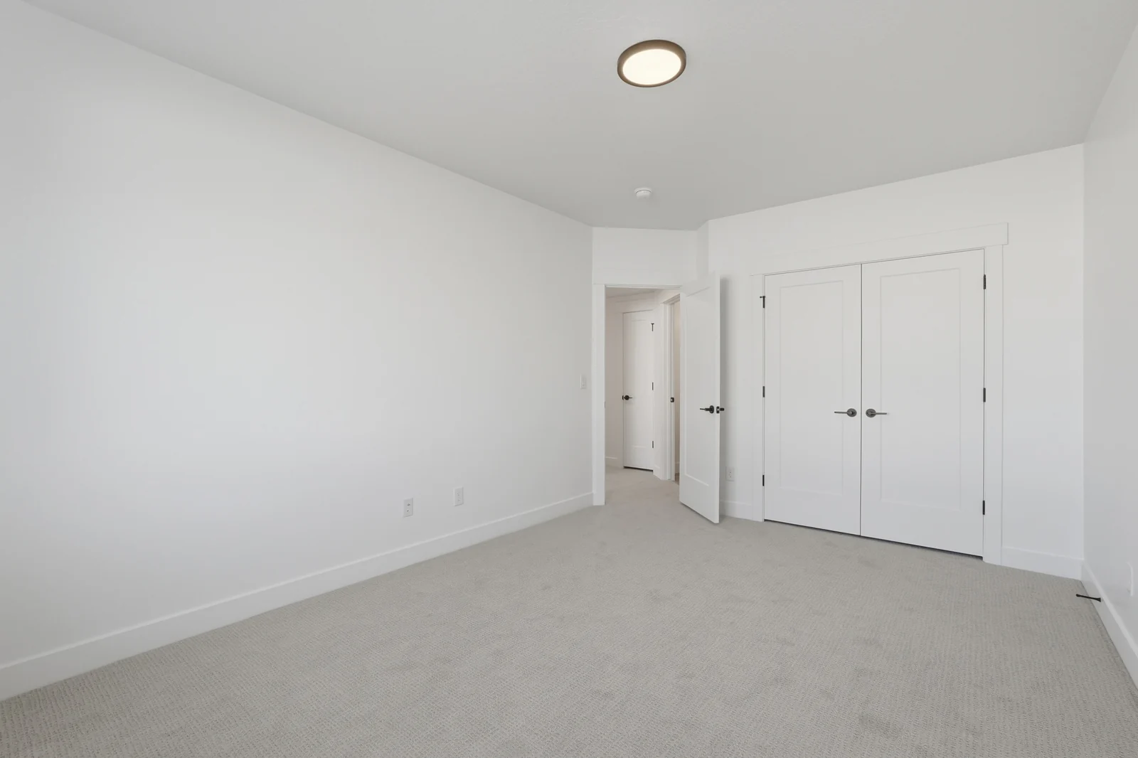 Empty carpeted bedroom with a window, double-door closet, recessed lighting, and white walls in Chestnut Modern MW302, Stansbury Park.
