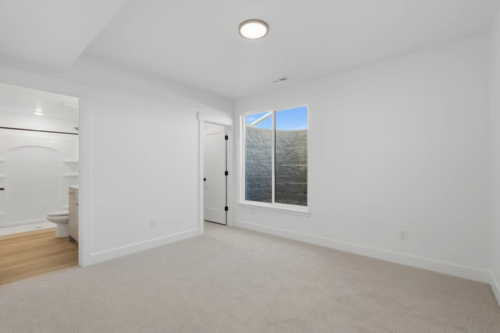 Carpeted bedroom with a window, white walls, recessed lighting, and an open doorway to the hall in Chestnut Modern MW302, Stansbury Park.