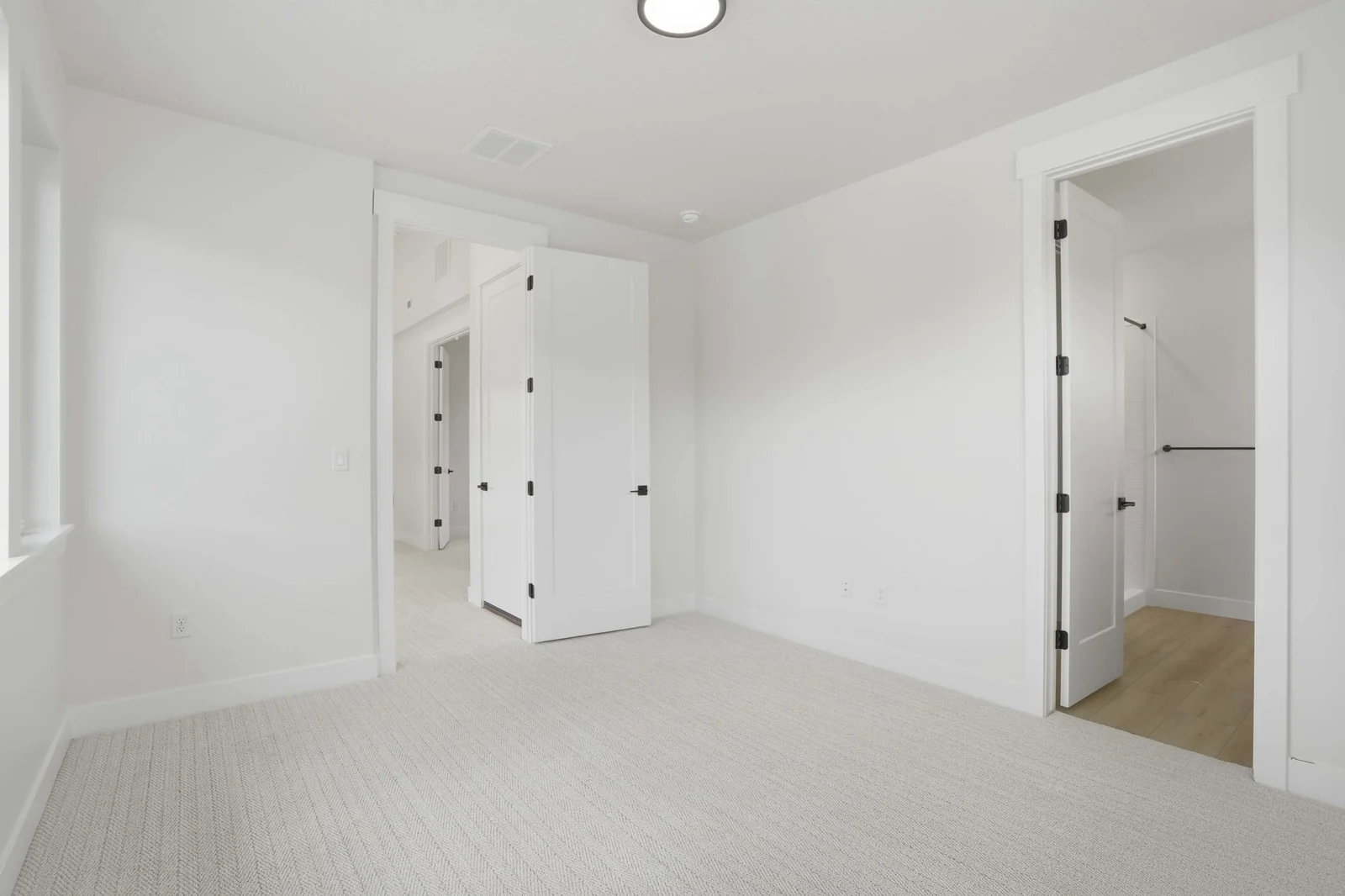 Unfurnished bedroom view with pale carpet, recessed lighting, white doors, and a wide passage toward the hall in the Denali model, American Fork.
