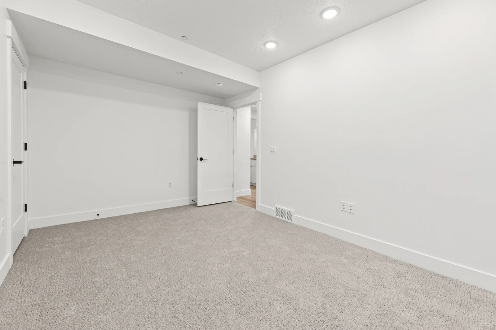 Unfurnished carpeted bedroom includes a window, white walls, recessed lighting, and a wide entry opening in Hawthorne Farmhouse, Ogden.