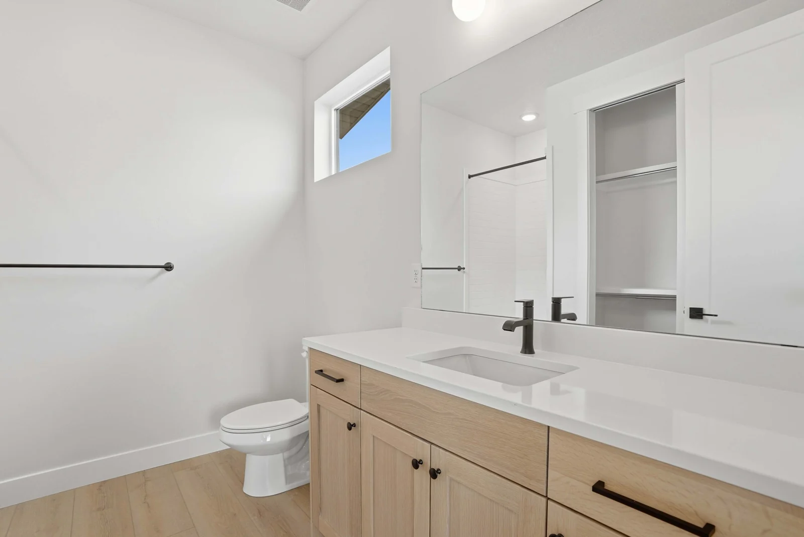 Bathroom with a wood vanity, white countertop, toilet, towel bar, and open built-in shelving in the Denali model, American Fork.