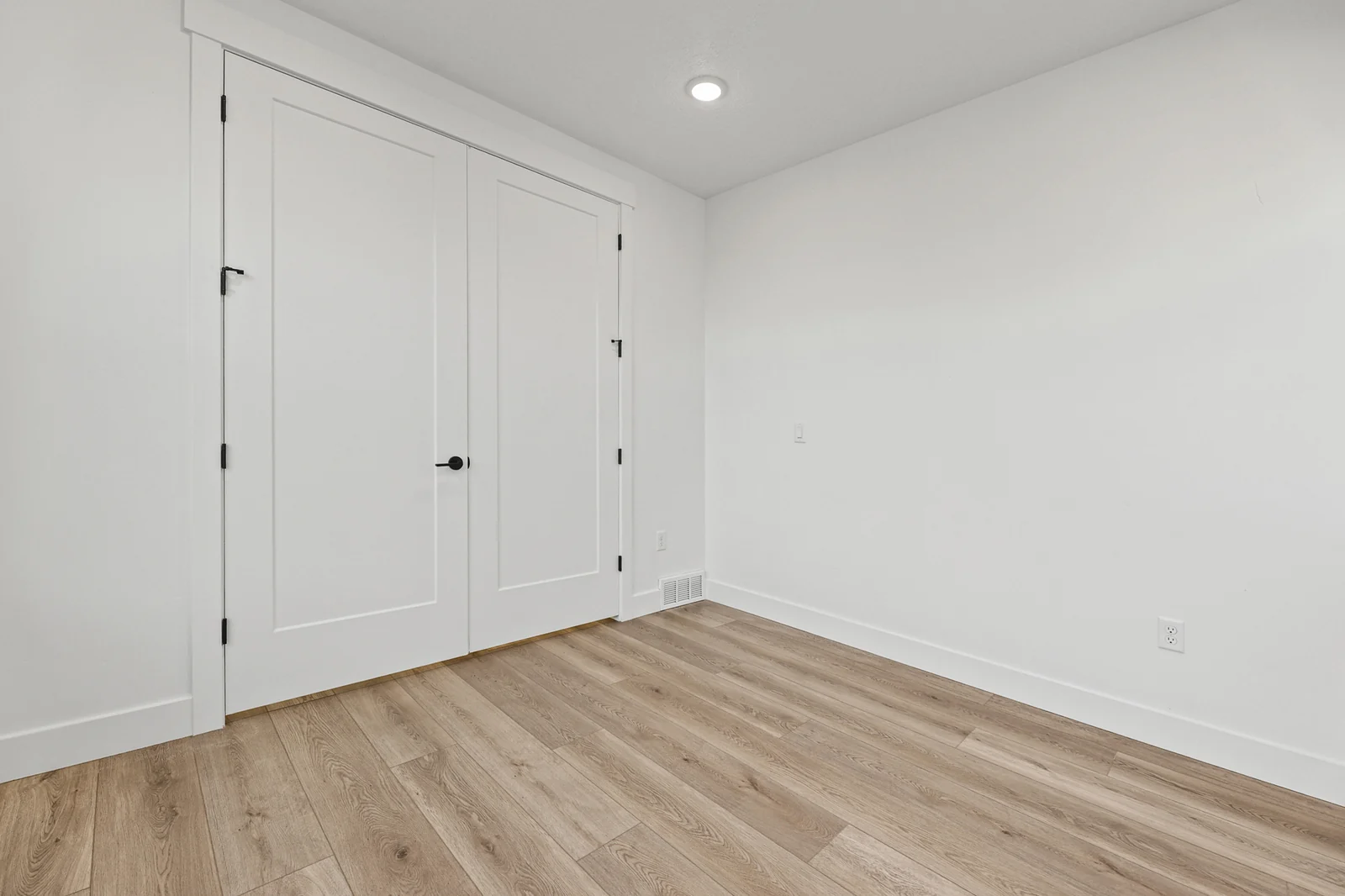 Unfurnished room with wood flooring includes double closet doors, white walls, and recessed lighting in Hawthorne Farmhouse, Ogden.