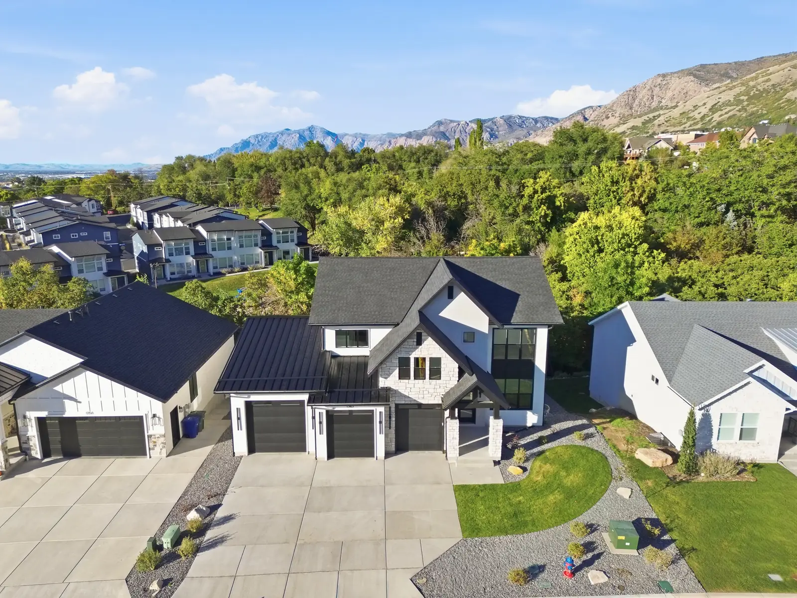 Aerial neighborhood view shows the home, adjacent residences, green hillside, and distant mountains in Hawthorne Farmhouse, Ogden.