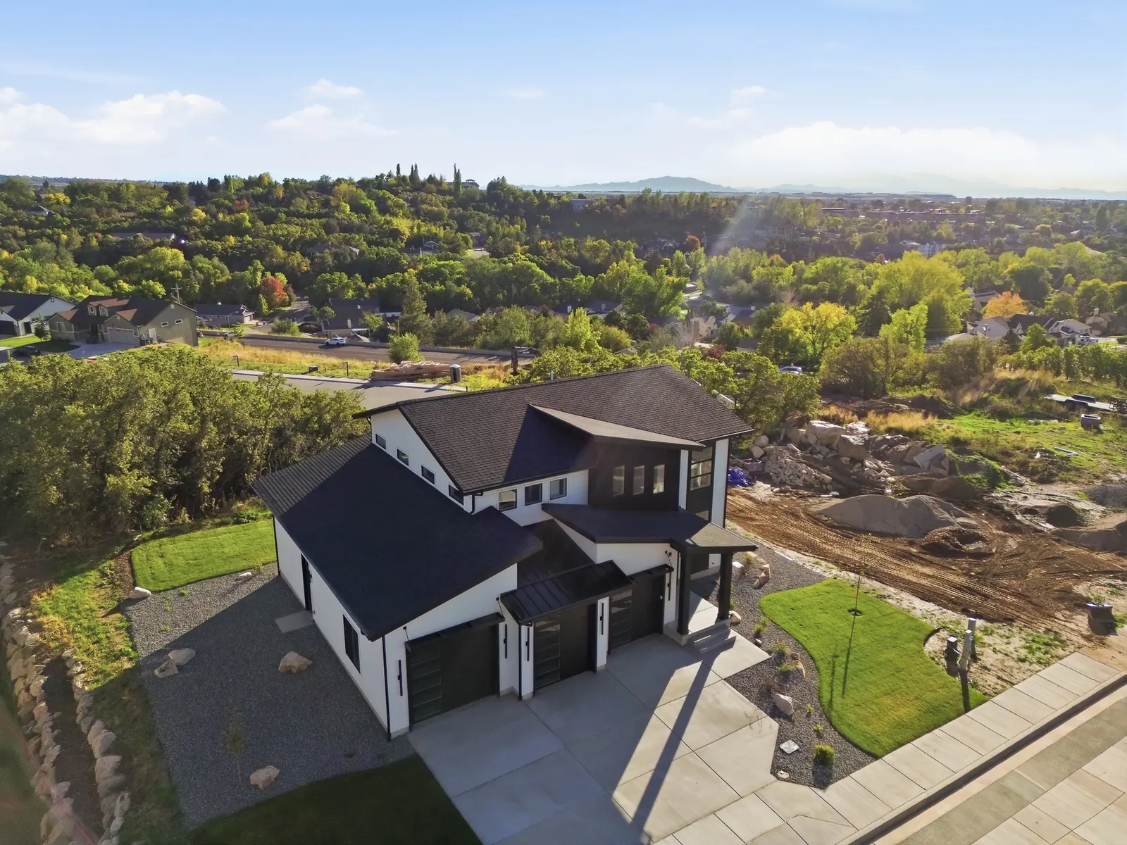 Aerial photograph of the home, concrete driveway, landscaped yard, nearby streets, and surrounding trees in Hawthorne Modern, Ogden.