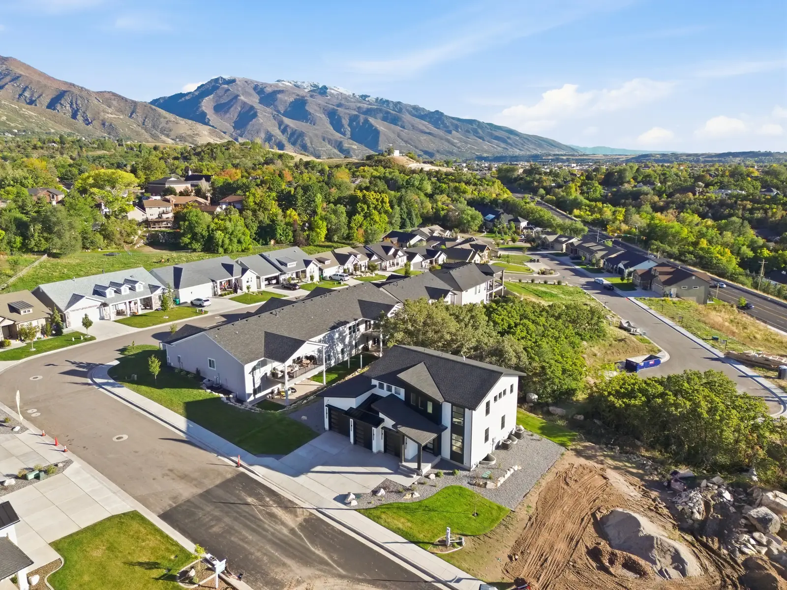 Aerial photograph of the home, surrounding neighborhood, green trees, open lots, and mountain backdrop in Hawthorne Modern, Ogden.