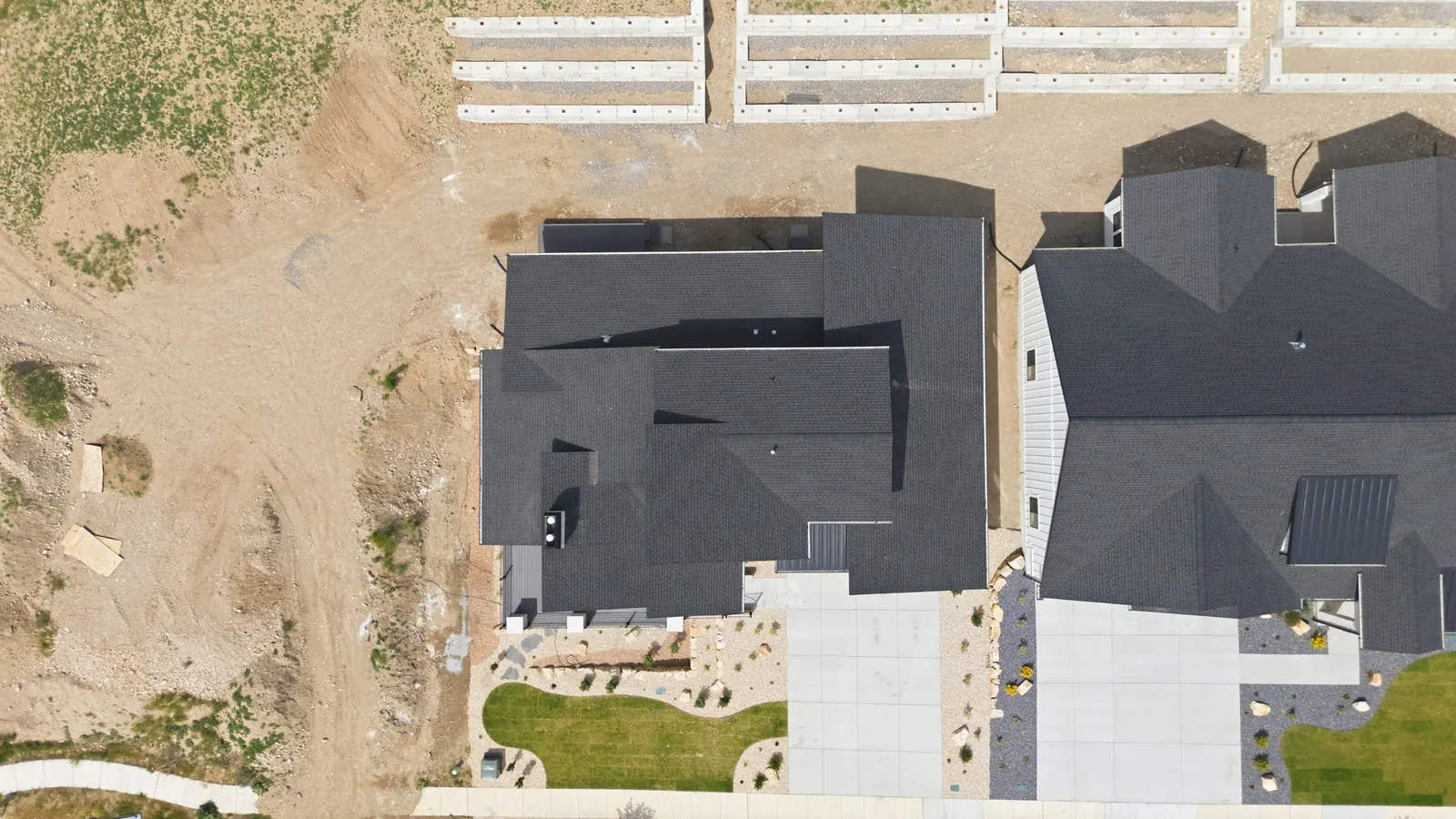 Top-down aerial view of the dark roof, driveway, landscaped front yard, and neighboring property lines in the Denali model, American Fork.