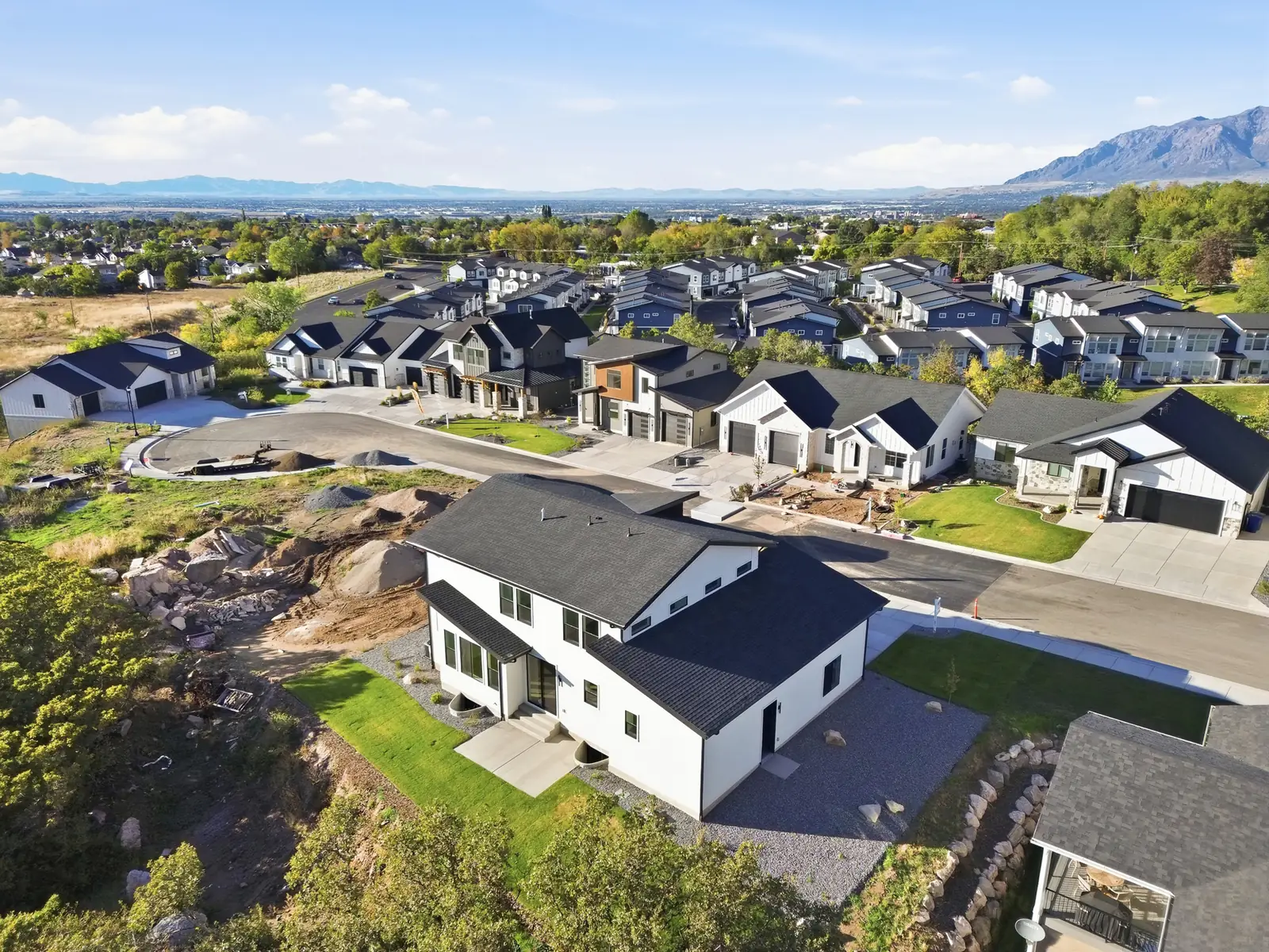 Aerial photograph showing the home, neighborhood streets, nearby houses, open ground, and distant mountain views in Hawthorne Modern, Ogden.