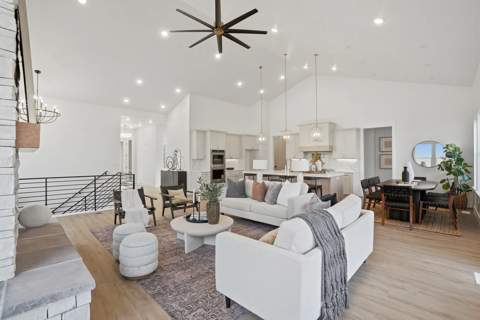 Living area with white sofas, kitchen island, dining space, and tall windows in Olympic BH08, American Fork.