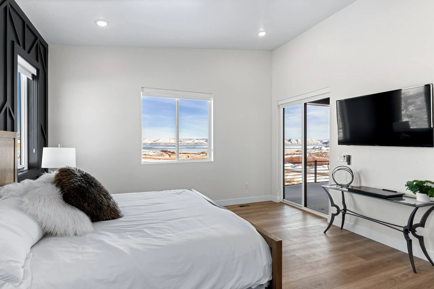 Bedroom with a white bed, compact writing desk, wall-mounted television, recessed lighting, and exterior-facing windows — Denali, Bear Lake.