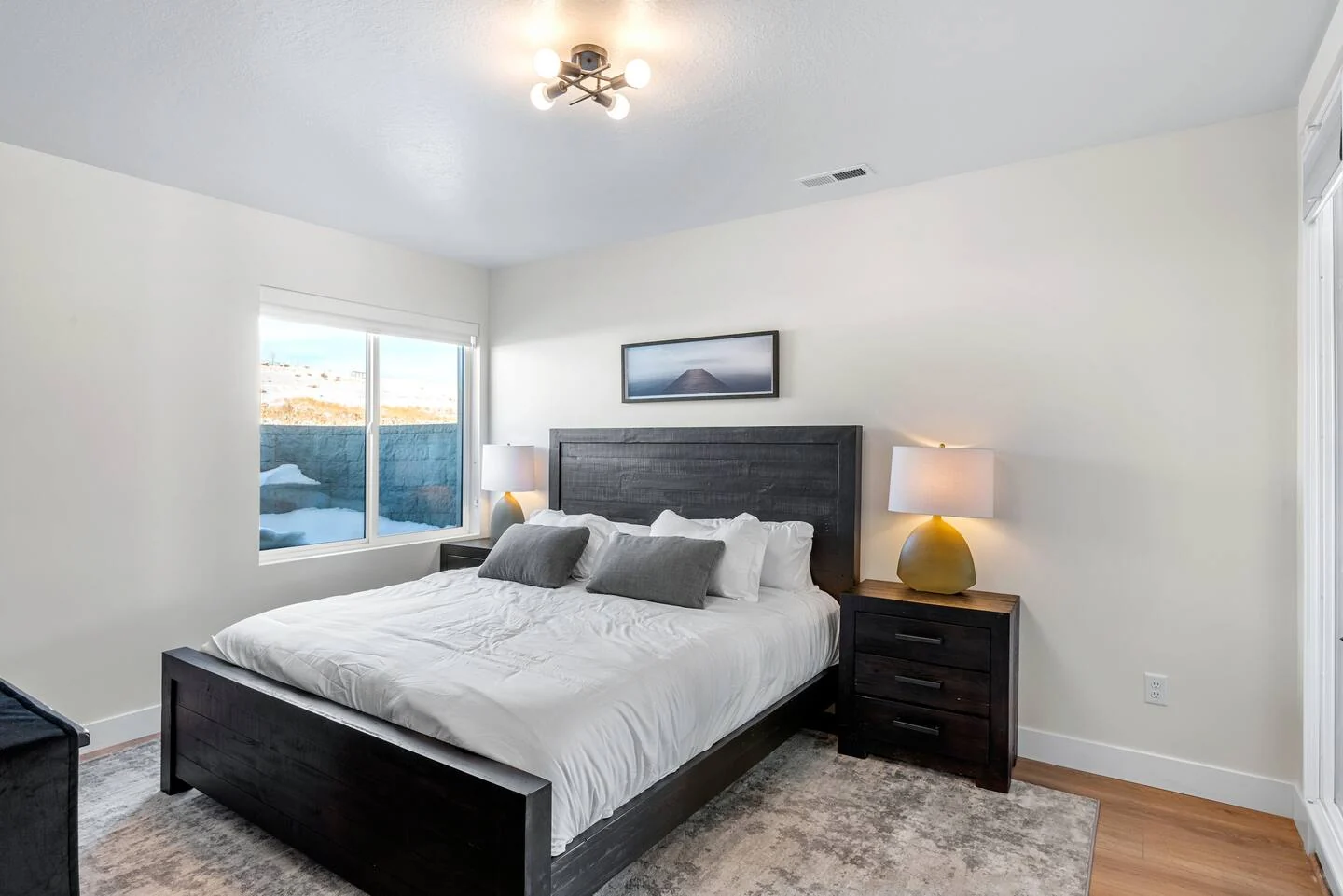 Bedroom with a dark wood bed frame, nightstands, gray rug, recessed lighting, and a window — Denali, Bear Lake.