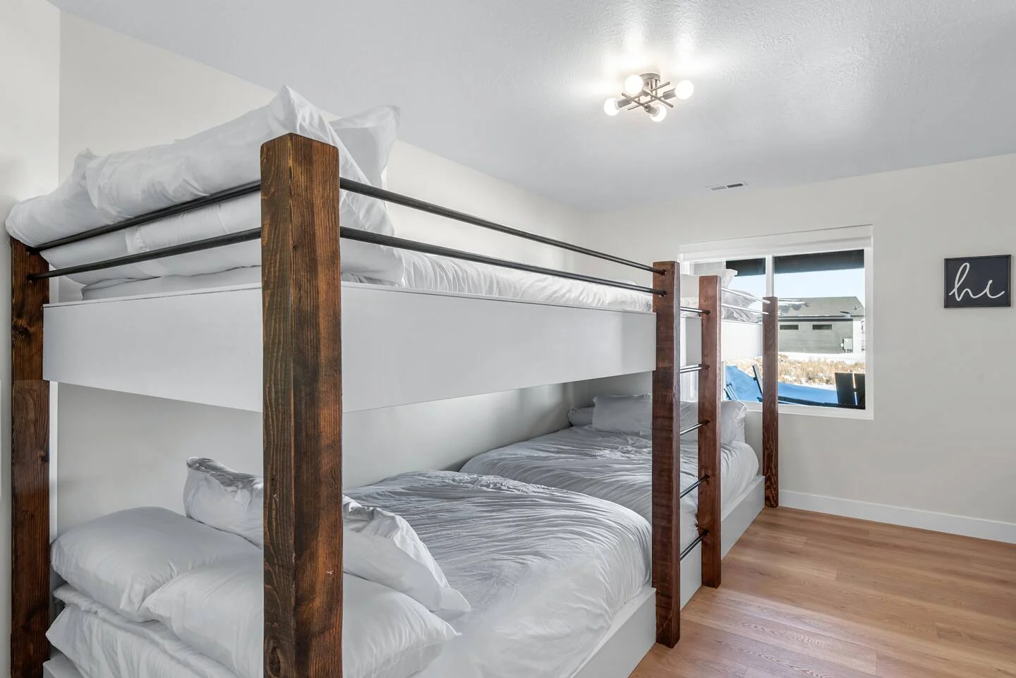 Bedroom furnished with wood bunk beds, white bedding, hardwood-style flooring, recessed lighting, and two exterior-facing windows — Denali, Bear Lake.