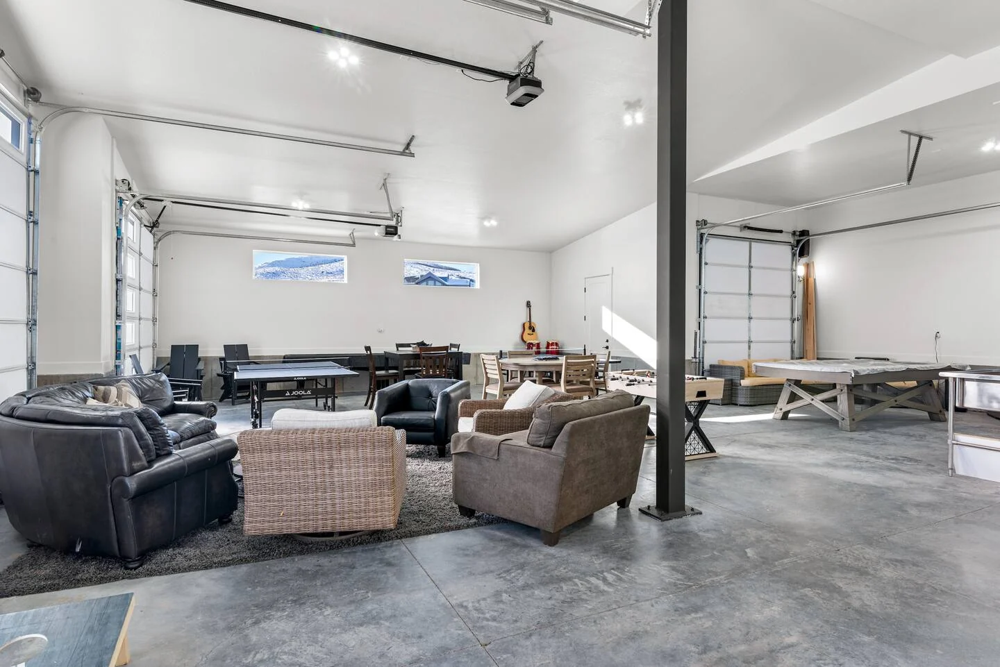 Garage interior with polished concrete floor, exposed structure, windowed doors, seating area, and overhead lighting — Denali, Bear Lake.