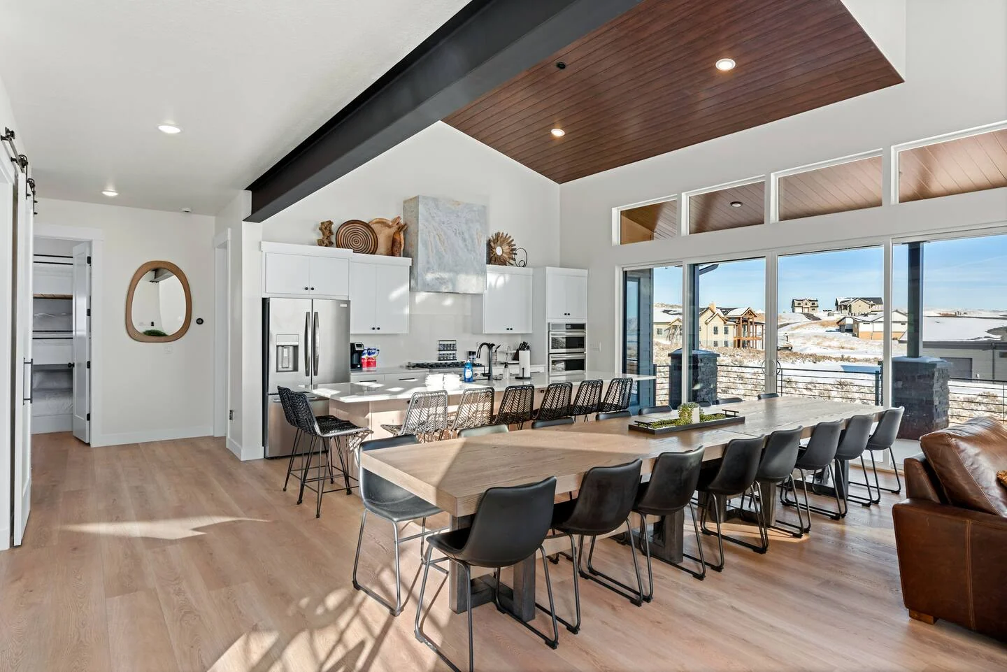 Open kitchen and dining area with a long island, stools, dark ceiling accent, and large windows — Denali, Bear Lake.