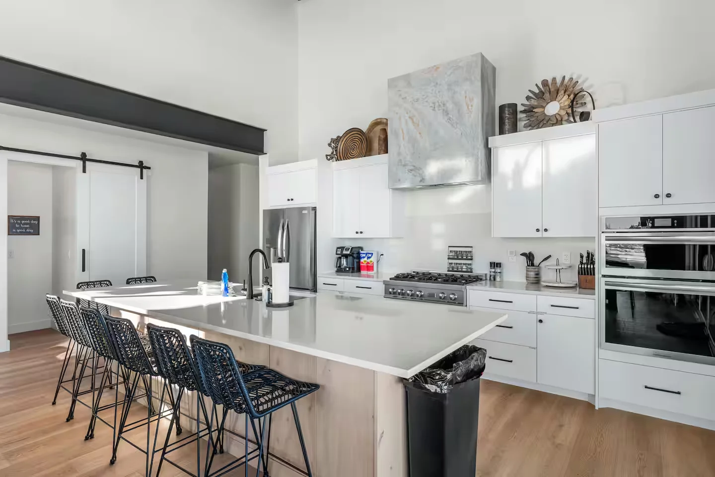 Kitchen with white cabinetry, dark peninsula seating, stainless refrigerator, tiled backsplash, built-in ovens, and pendant lighting — Denali, Bear Lake.