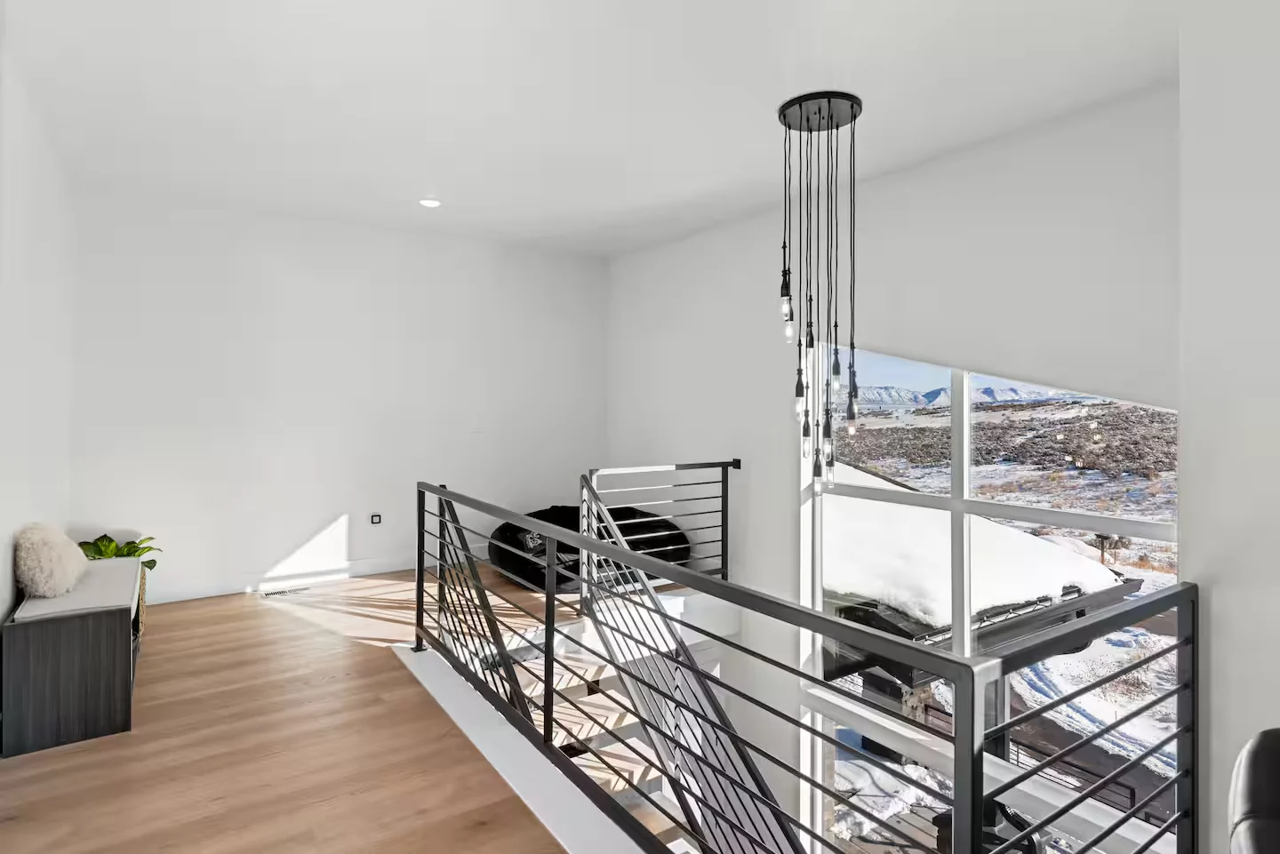 Open loft overlook with black railings, pale wood flooring, pendant lights, high ceiling, and window views — Denali, Bear Lake.