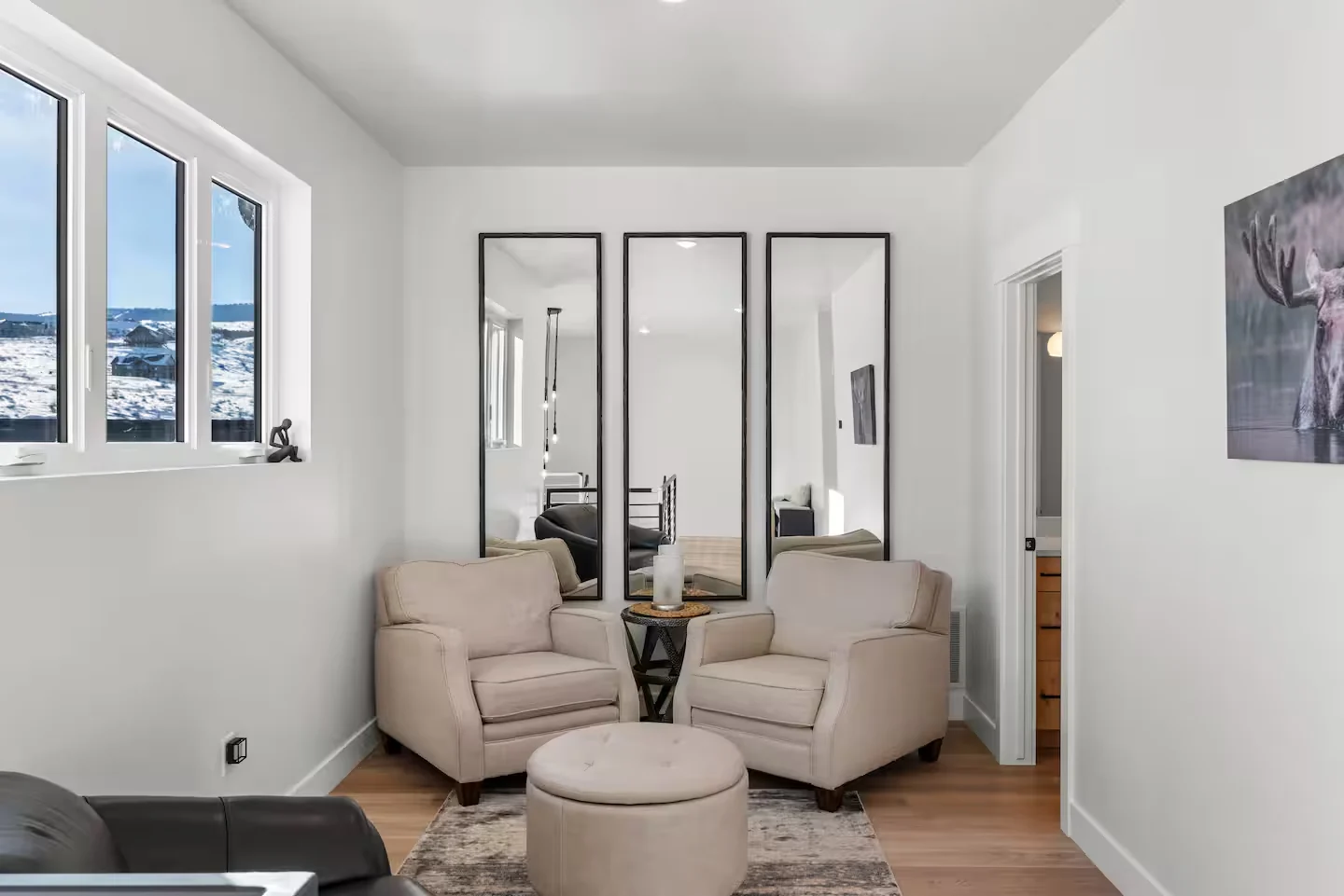 Loft sitting area with two chairs, small ottoman, mirrored wall panels, recessed lights, and tall windows — Denali, Bear Lake.