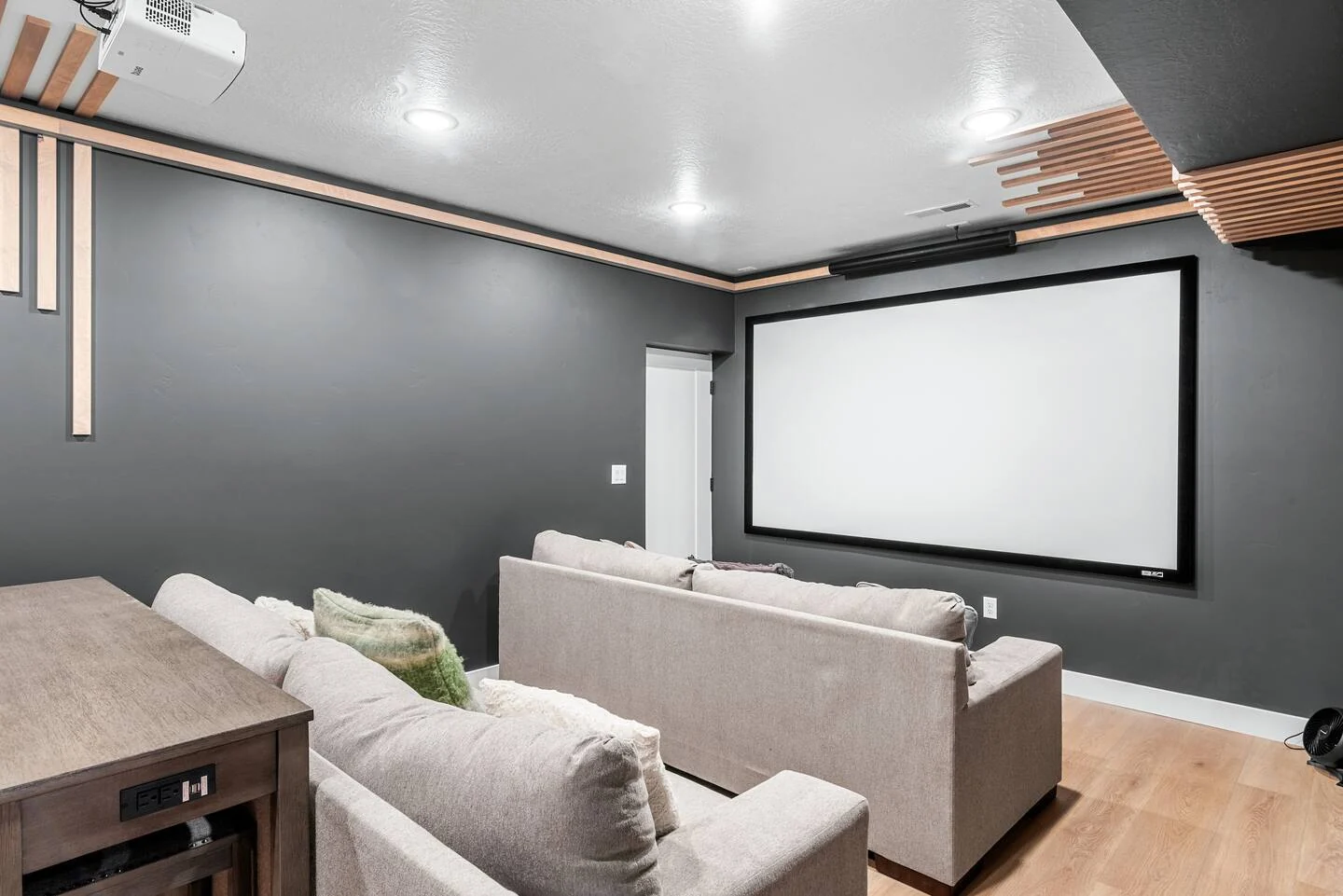 Theater room with a large projection screen, pale sectional seating, dark walls, ceiling accents, and recessed lights — Denali, Bear Lake.