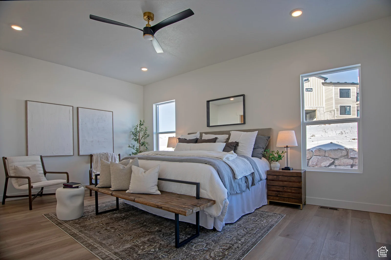 Primary bedroom photo showing a large bed, bench, reading chairs, bedside tables, ceiling fan, and snowy window views — Olympic, Bear Lake.