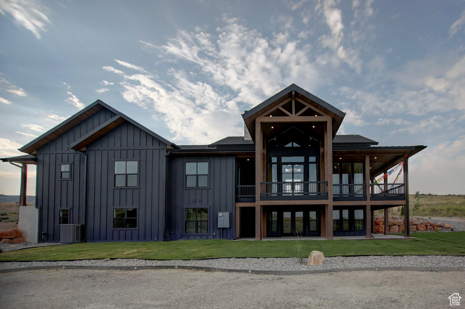 Rear exterior view of the dark-sided home with a covered upper deck and lawn in Pinnacle, Bear Lake.