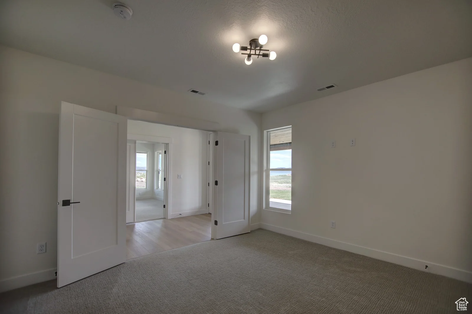 Unfurnished basement bedroom with carpet, an open door, and a large window in Pinnacle, Bear Lake.