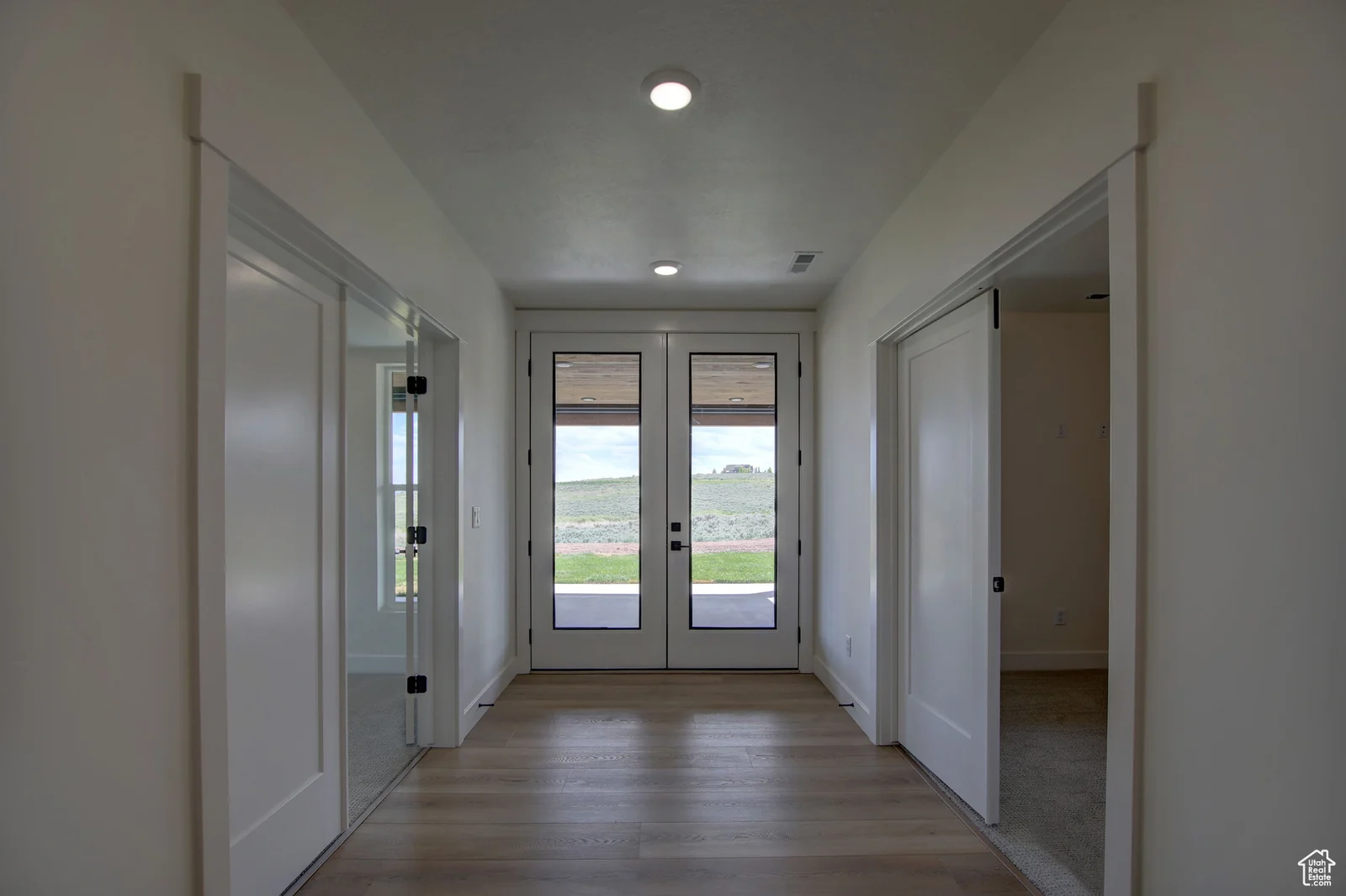Basement hallway with wood-look flooring, multiple doorways, and glass doors leading outside in Pinnacle, Bear Lake.