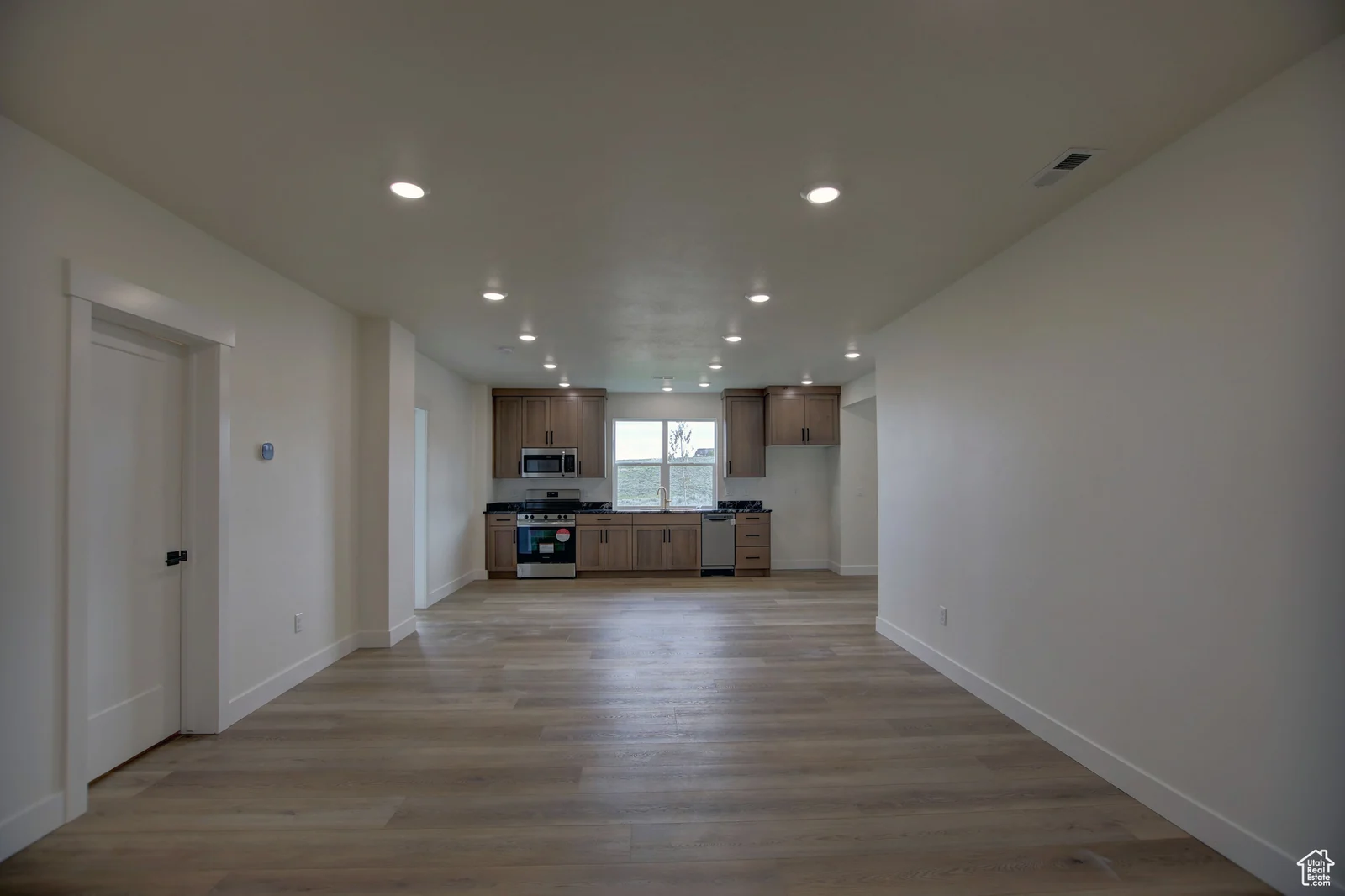 Open basement living area with wood-look flooring, recessed lights, and a kitchen along the back wall in Pinnacle, Bear Lake.