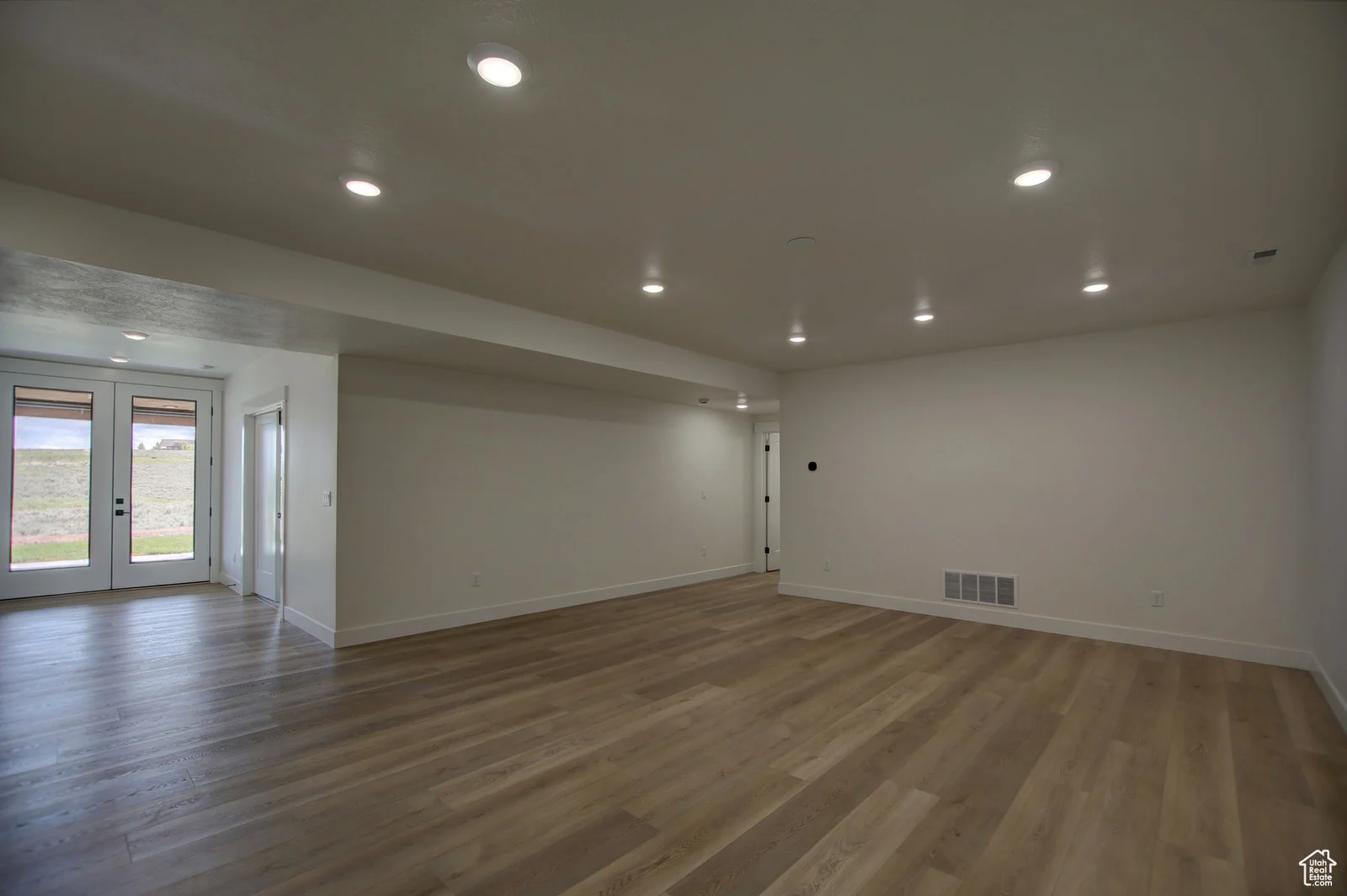 Unfurnished basement living room with wood-look flooring, recessed lighting, and glass doors to an exterior area in Pinnacle, Bear Lake.