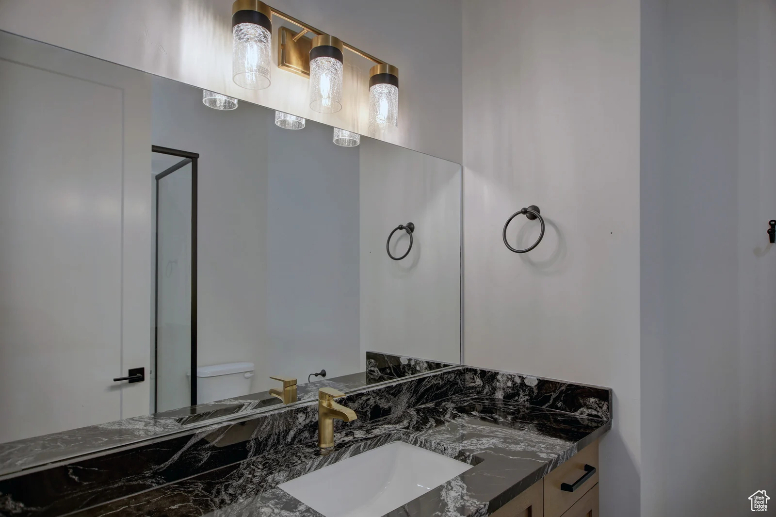 Bathroom with double sinks, dark stone-look counter, large mirror, and black-framed glass shower in Pinnacle, Bear Lake.