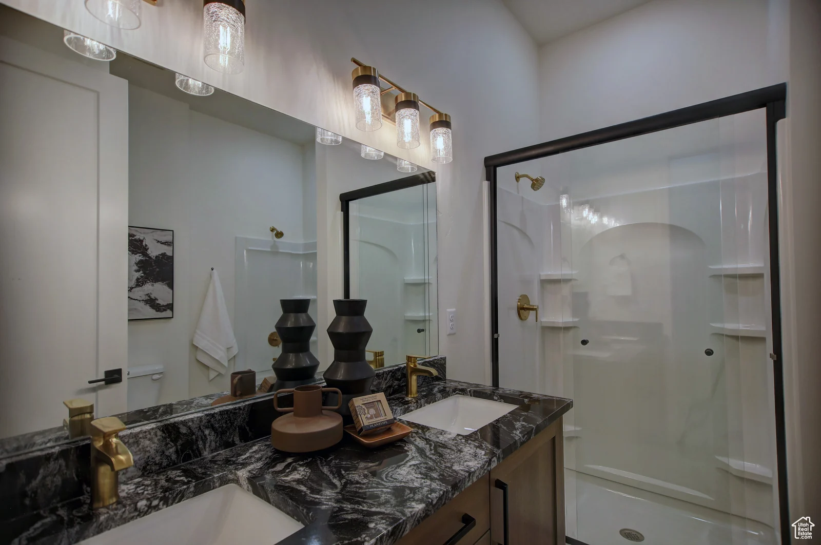 Bathroom with a wood vanity, dark stone-look counter, decorative mirror, and glass-enclosed shower in Pinnacle, Bear Lake.
