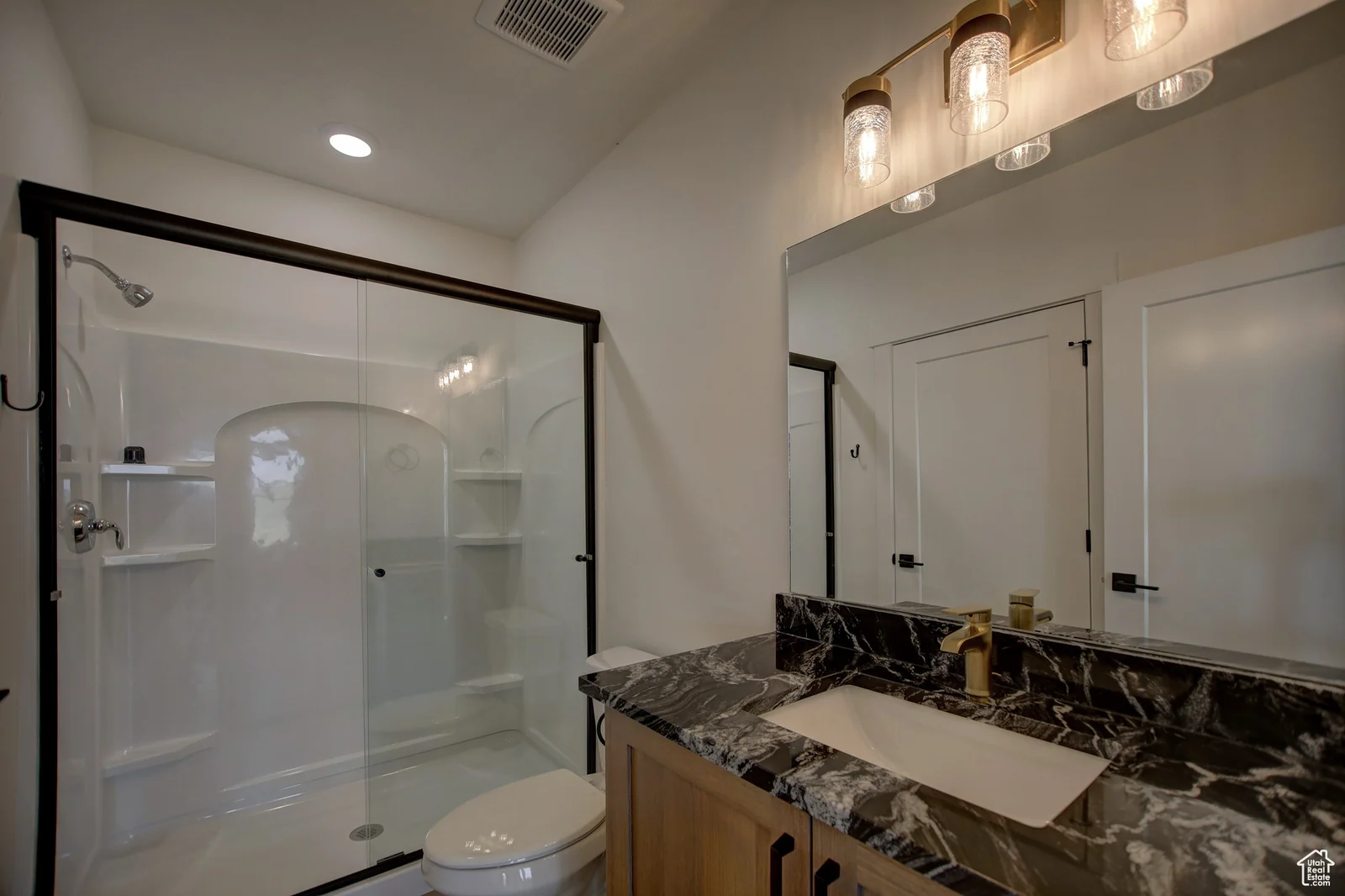 Bathroom vanity with a dark stone-look counter, vessel sink, framed mirror, and glass shower in Pinnacle, Bear Lake.