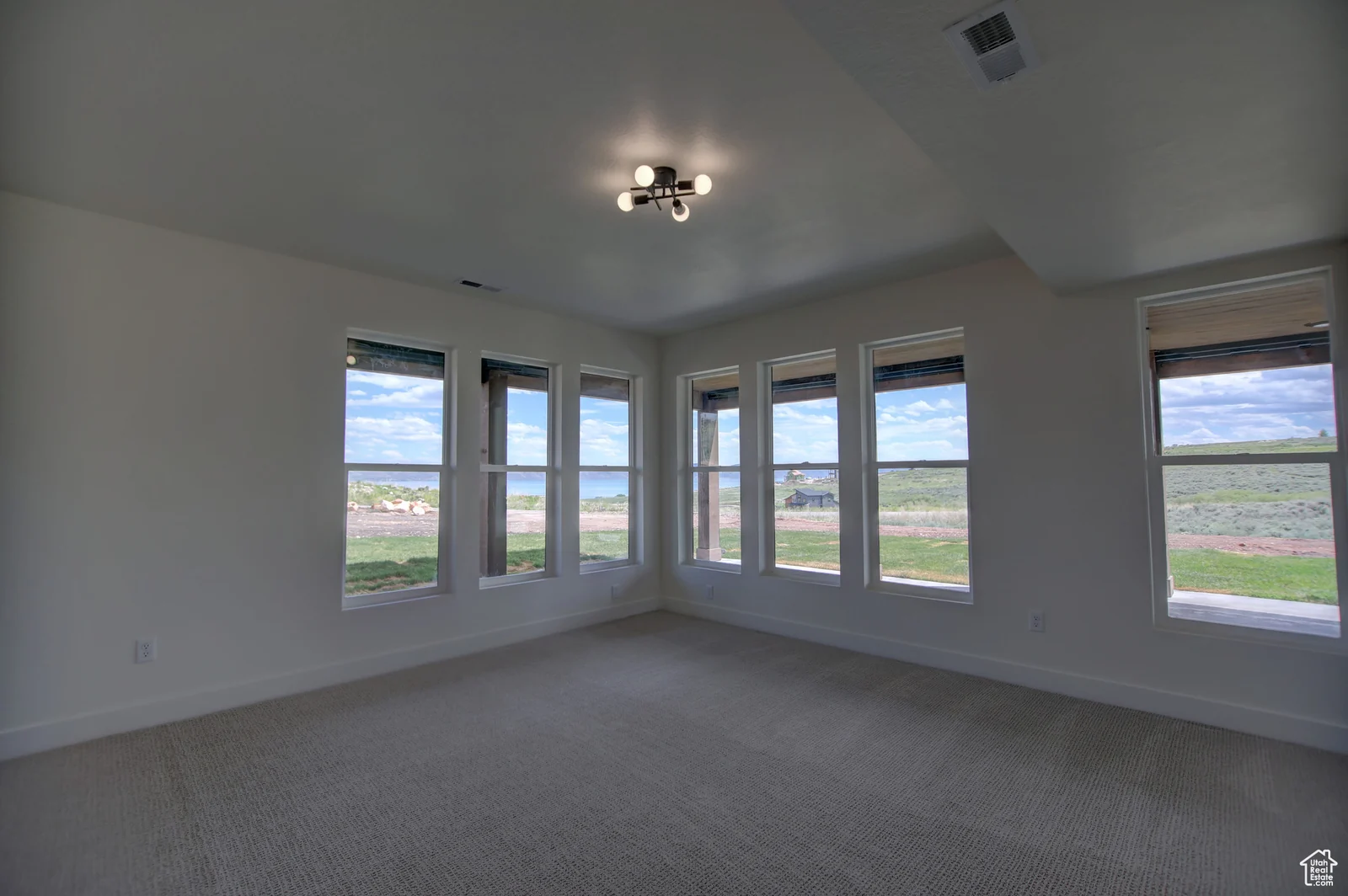 Unfurnished carpeted bedroom with a ceiling fixture and a wall of corner windows in Pinnacle, Bear Lake.