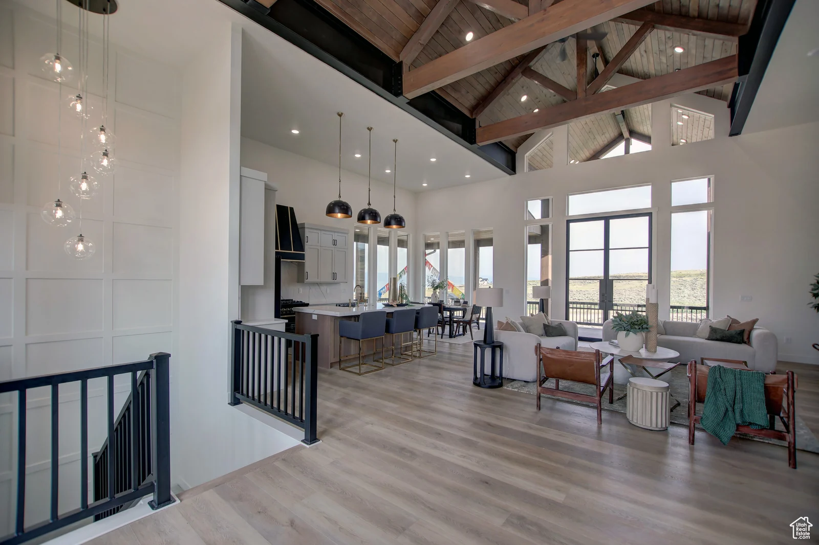 View from the stair landing into the vaulted great room with kitchen, seating, and pendant lights in Pinnacle, Bear Lake.