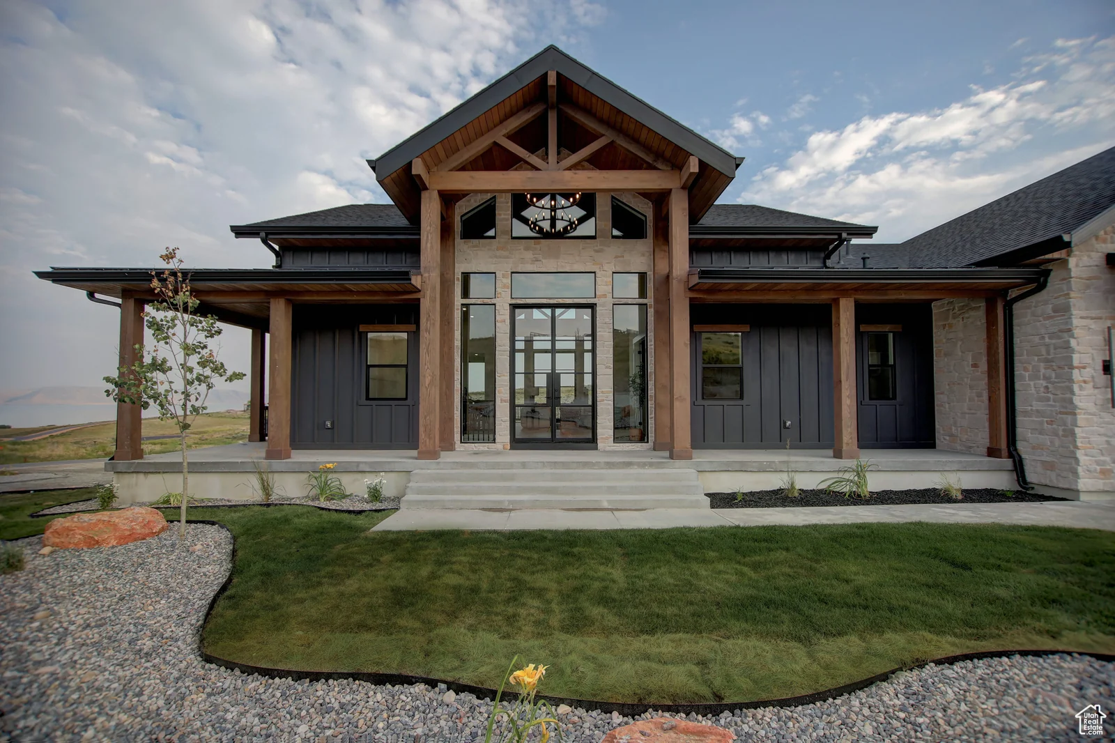 Front exterior with a tall covered entry, broad steps, wood beams, dark siding, and lawn in Pinnacle, Bear Lake.