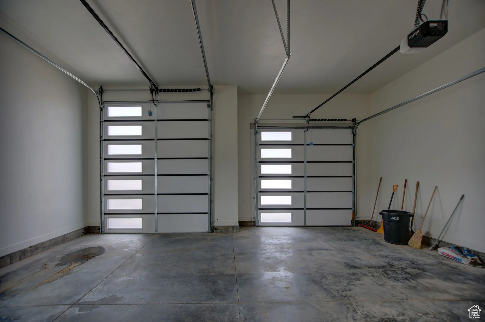 Three-bay garage interior with concrete floor, modern garage doors, windows, and wall-mounted tools in Pinnacle, Bear Lake.