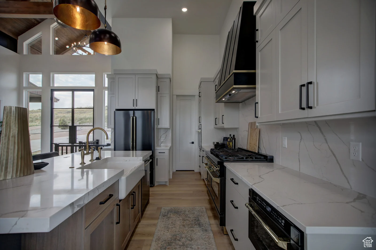 Kitchen with white cabinetry, large island, dark range hood, pendant lights, and a view toward the dining area in Pinnacle, Bear Lake.