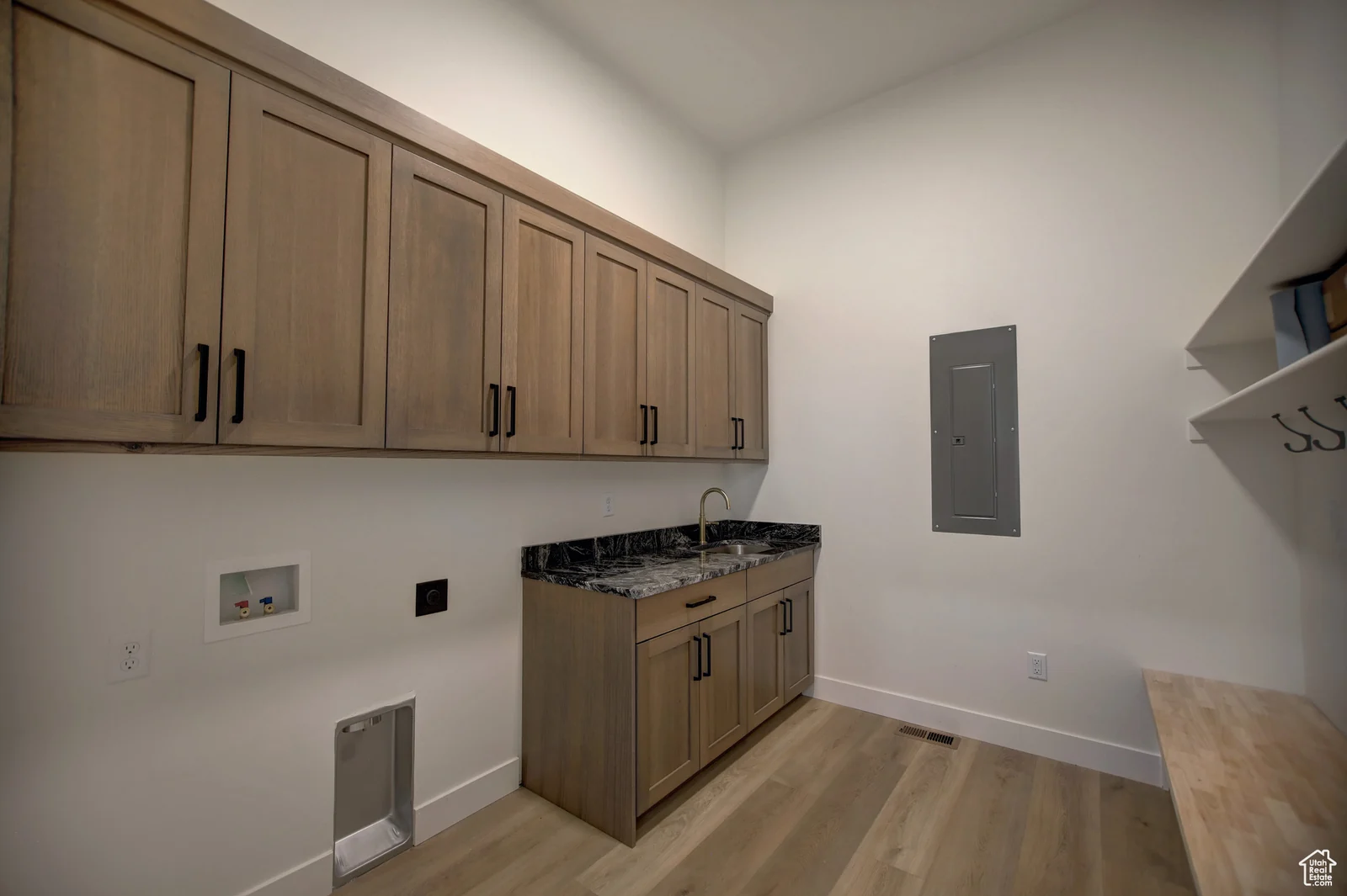 Laundry room with wood cabinetry, dark counter, utility hookups, and wood-look flooring in Pinnacle, Bear Lake.