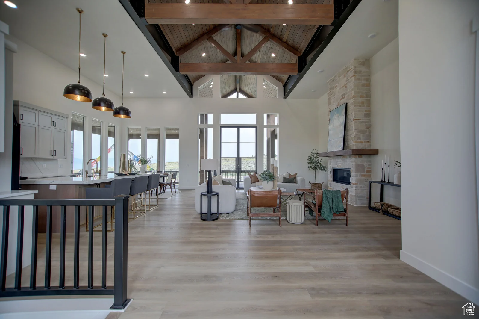 Open great room with exposed trusses, kitchen island, seating area, and stone fireplace in Pinnacle, Bear Lake.